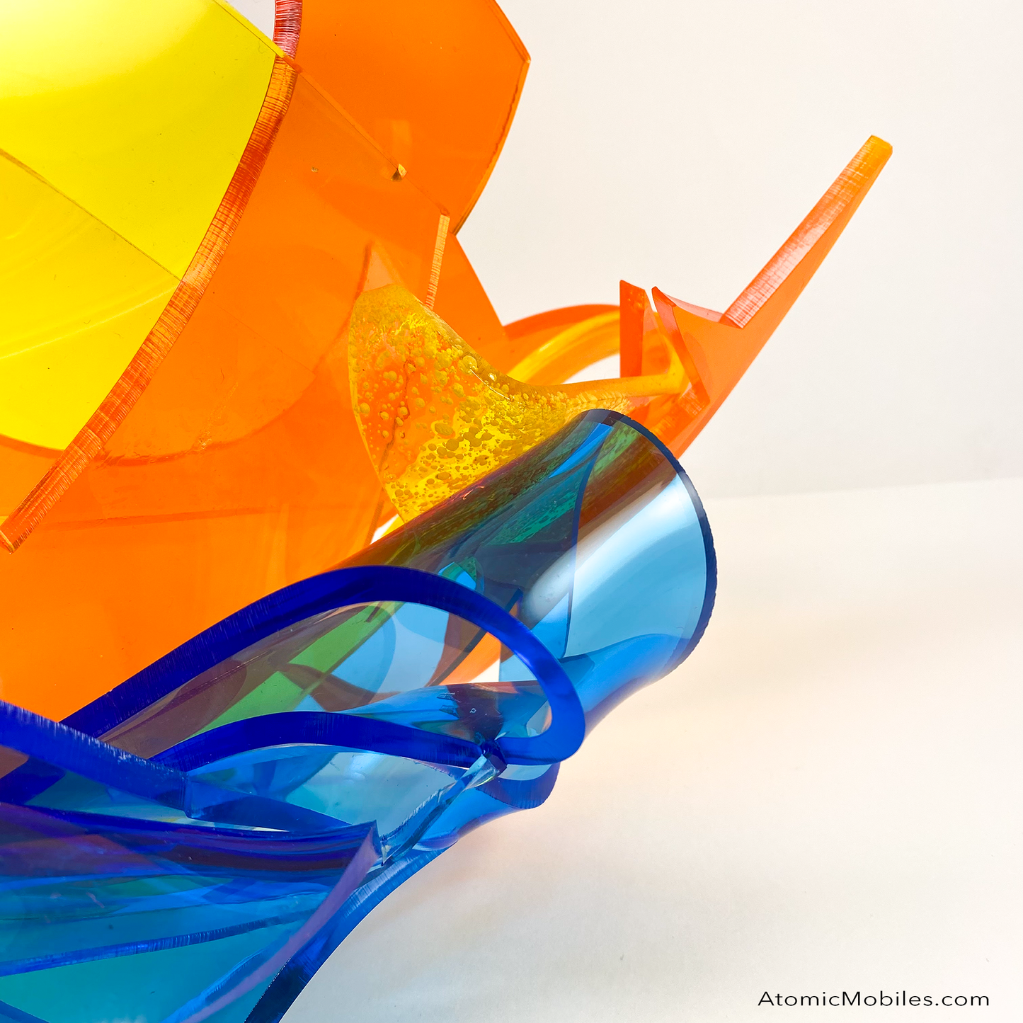 Side closeup view of Dream Abstract Art Sculpture from the Sculptura Collection of incredibly unique art sculptures hand made with earth-friendly upcycled acrylic plexiglass by Debra Ann of AtomicMobiles.com in Los Angeles, featuring bold colors of clear orange, clear blue, and clear yellow