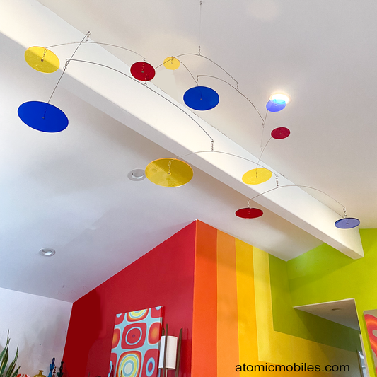 LOOK UP! Art Mobile hanging in colorful living room with 70s abstract bold color mural - mobile with transparent navy, red, and yellow acrylic plexiglass circles by AtomicMobiles.com