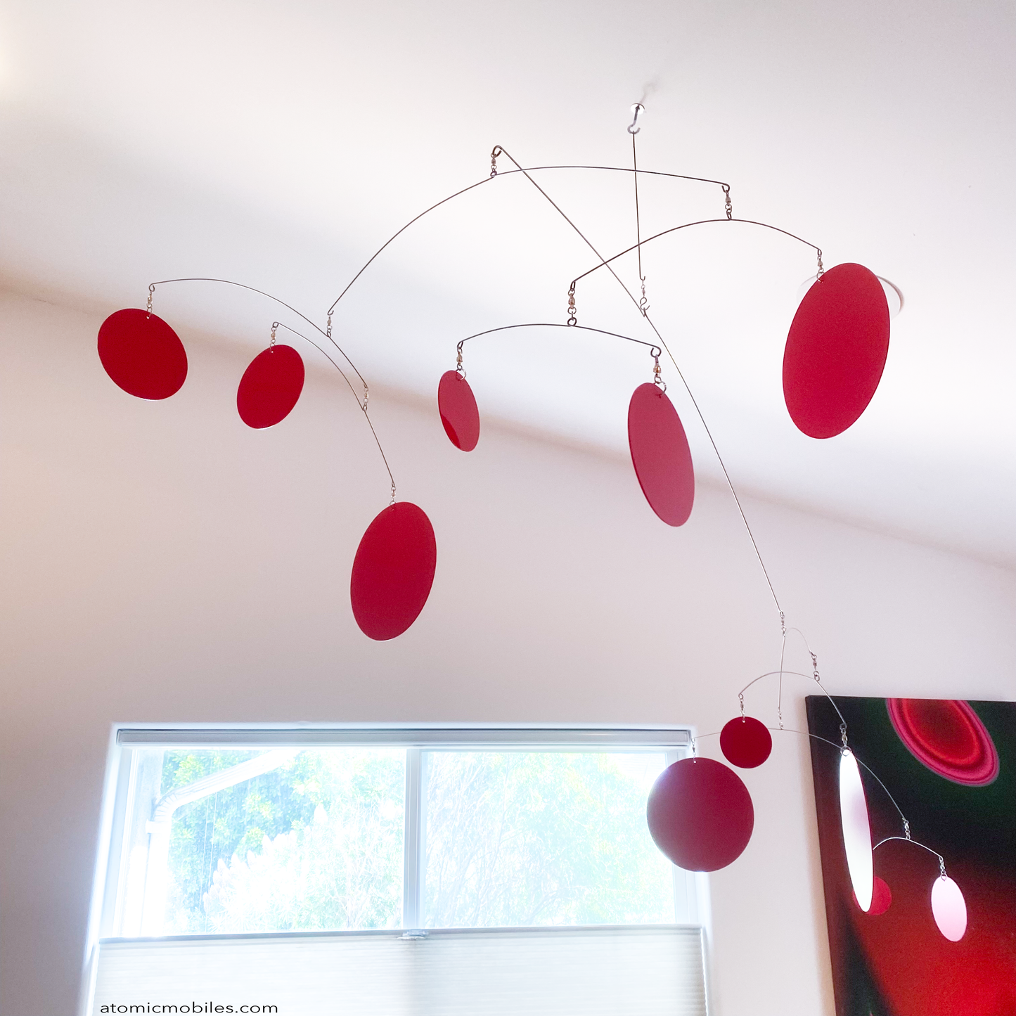 View from below XL Red Kinetic Hangng Art Mobile by AtomicMobiles.com - large red circles in large mobile in dining room over wood table made in Los Angeles