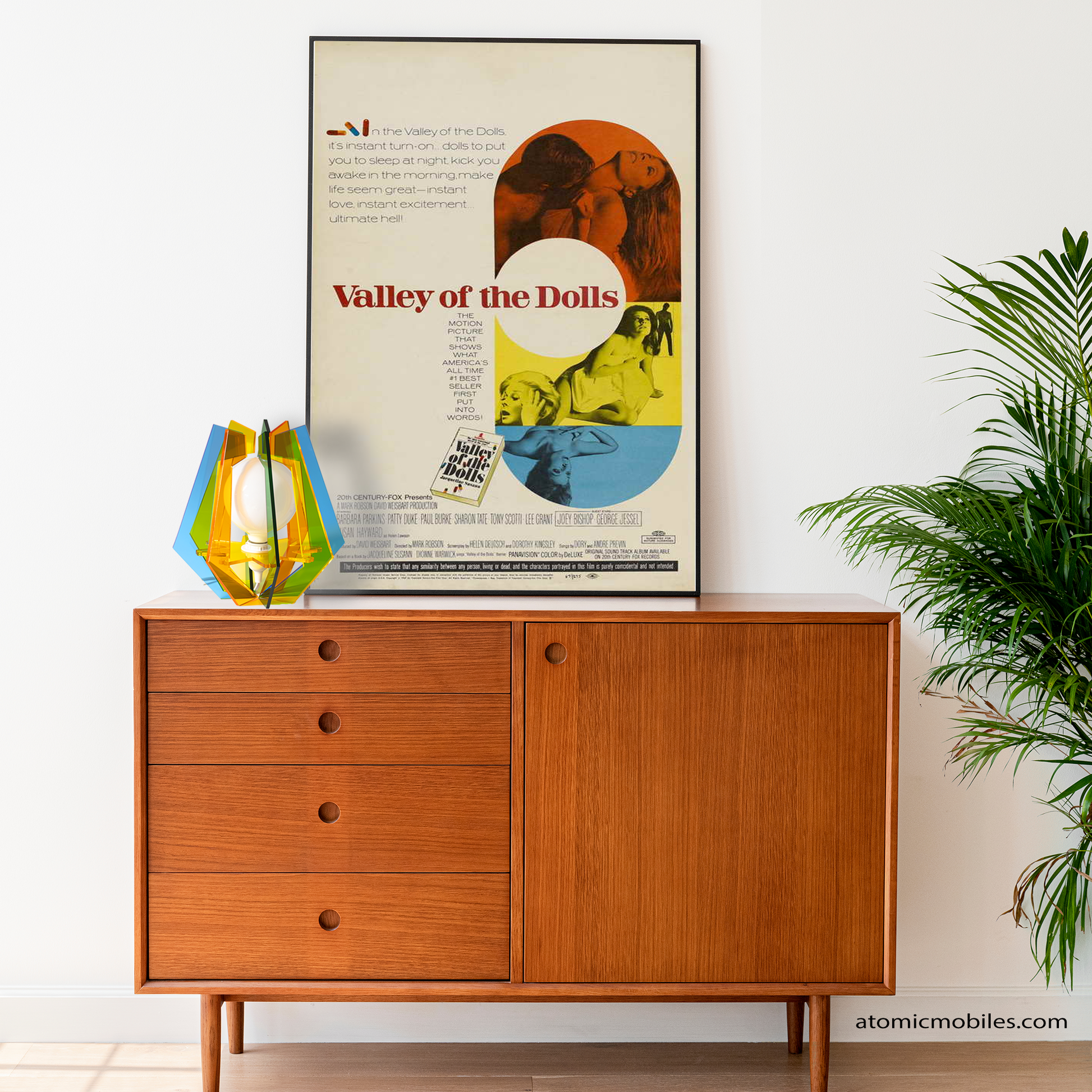 ASTROLUMA Space Age Retro Table Top Lamp in clear color acrylic plexiglass plastic with large globe light bulb on a danish mid century modern credenza sideboard furniture and movie poster with plant - lamp made in Los Angeles, California USA by AtomicMobiles.com