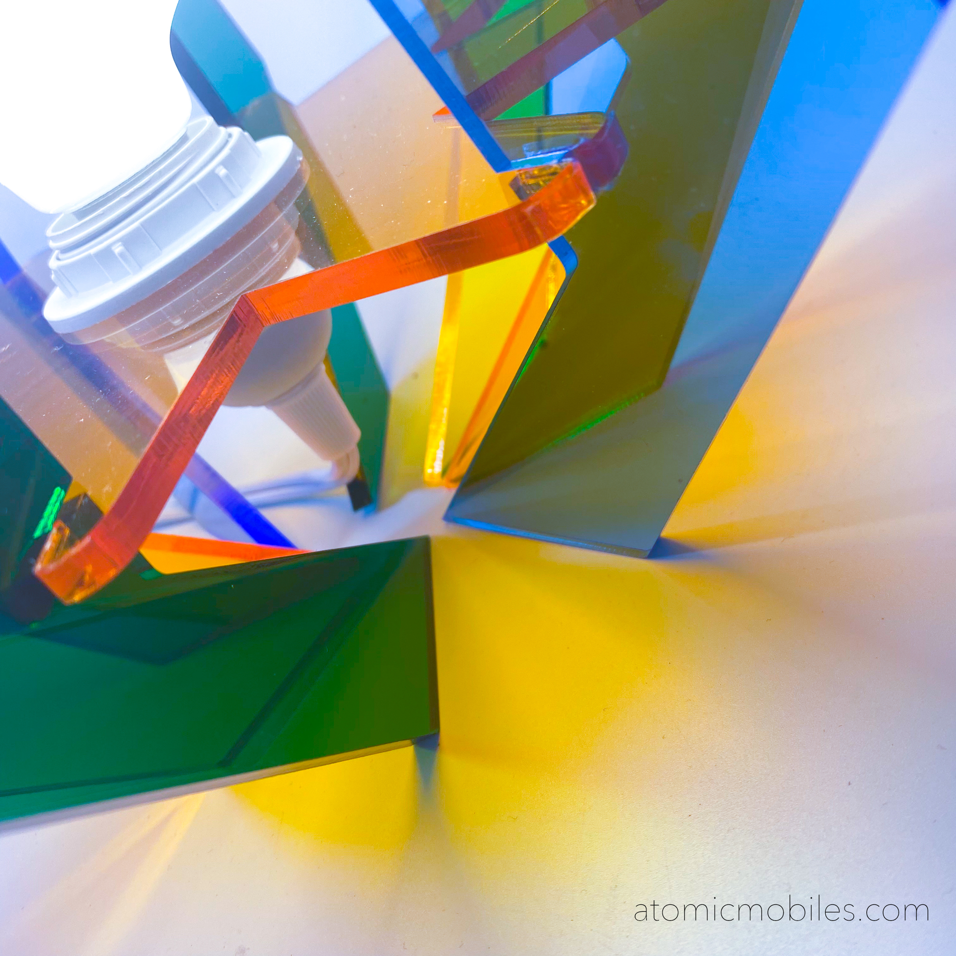 Closeup of lit up 1971 Space Age Lamp in clear acrylic colors of orange, blue, yellow, and green- retro mid century modern groovy lighting by AtomicMobiles.com