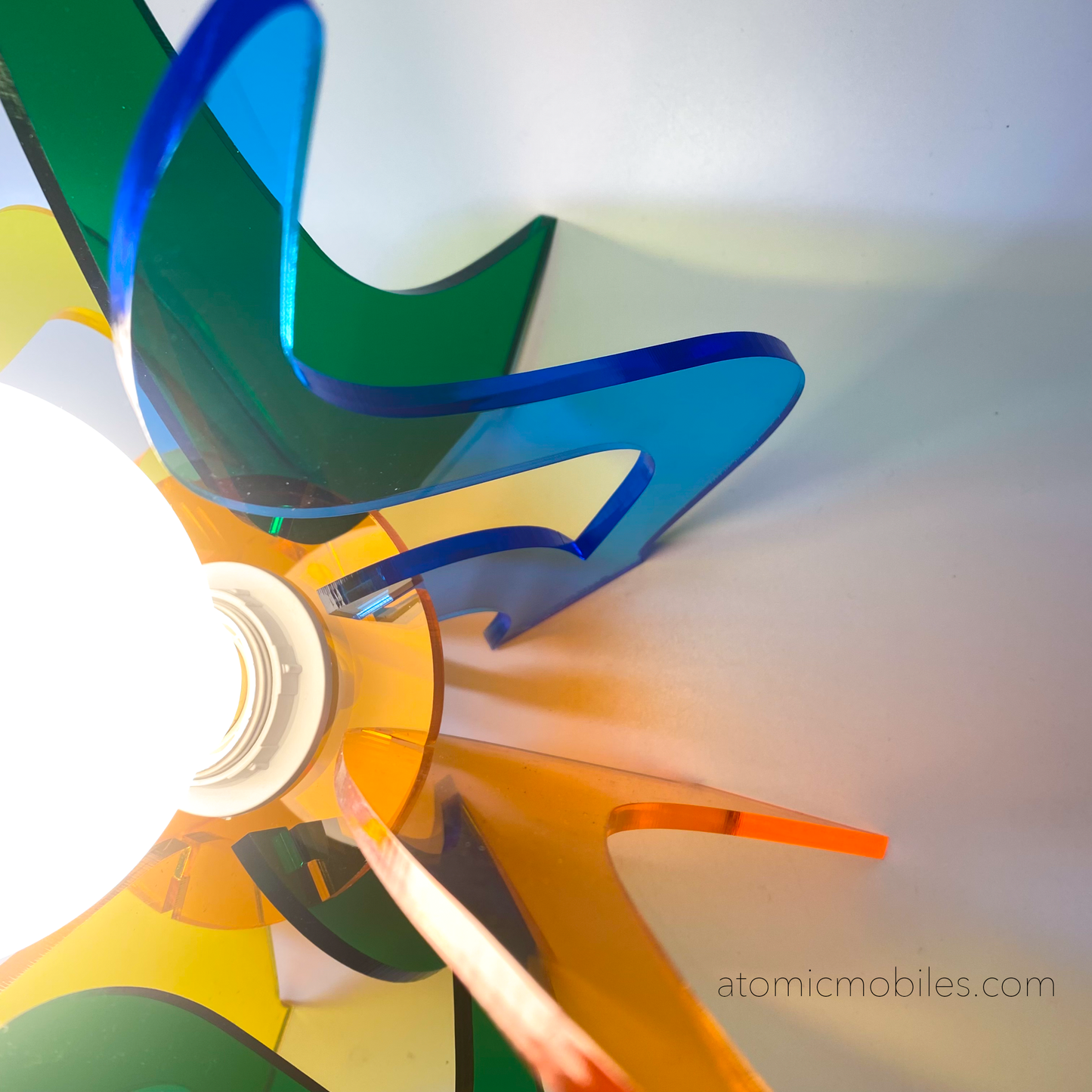 Closeup of lit up Genie Space Age Lamp in clear acrylic colors of orange, blue, yellow, and green- retro mid century modern groovy lighting by AtomicMobiles.com