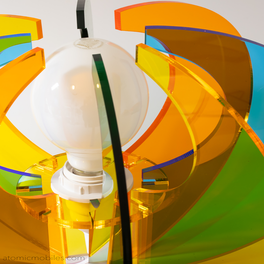 Closeup of ASTRO LUMA ORBIT retro mid century modern style lamp in clear orange, green, yellow, and blue acrylic plexiglass by AtomicMobiles.com