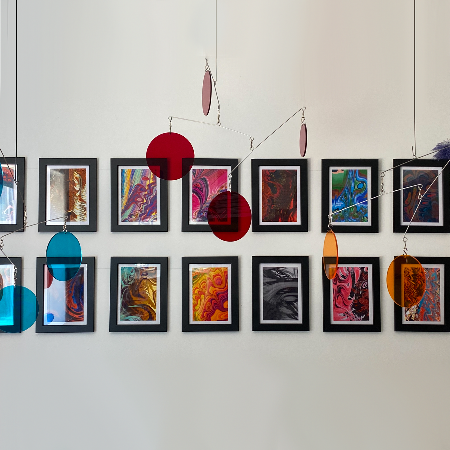 Clear ed teal and orange acrylic Atomic Mobiles in front of MiniMOD abstract art prints by AtomicMobiles.com