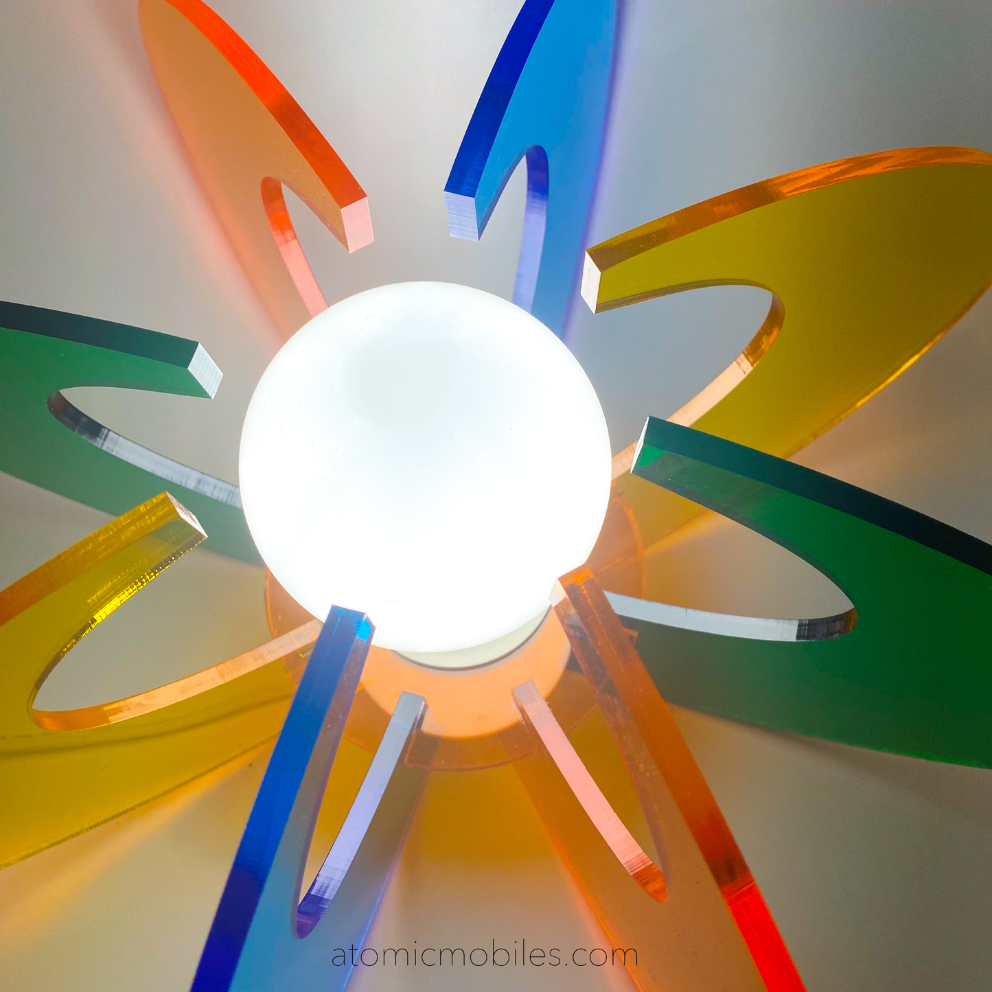 View from top of lit up Orbit Space Age Lamp in clear acrylic colors of orange, blue, yellow, and green- retro mid century modern groovy lighting by AtomicMobiles.com