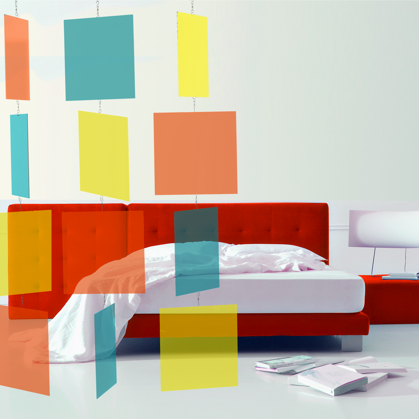 Modern bedroom with red velvet bed frame, white floor and walls, lamp, and books with Palm Springs MODcast hanging art mobile in mid century modern colors of Orange, Aqua Blue, and Yellow by AtomicMobiles.com