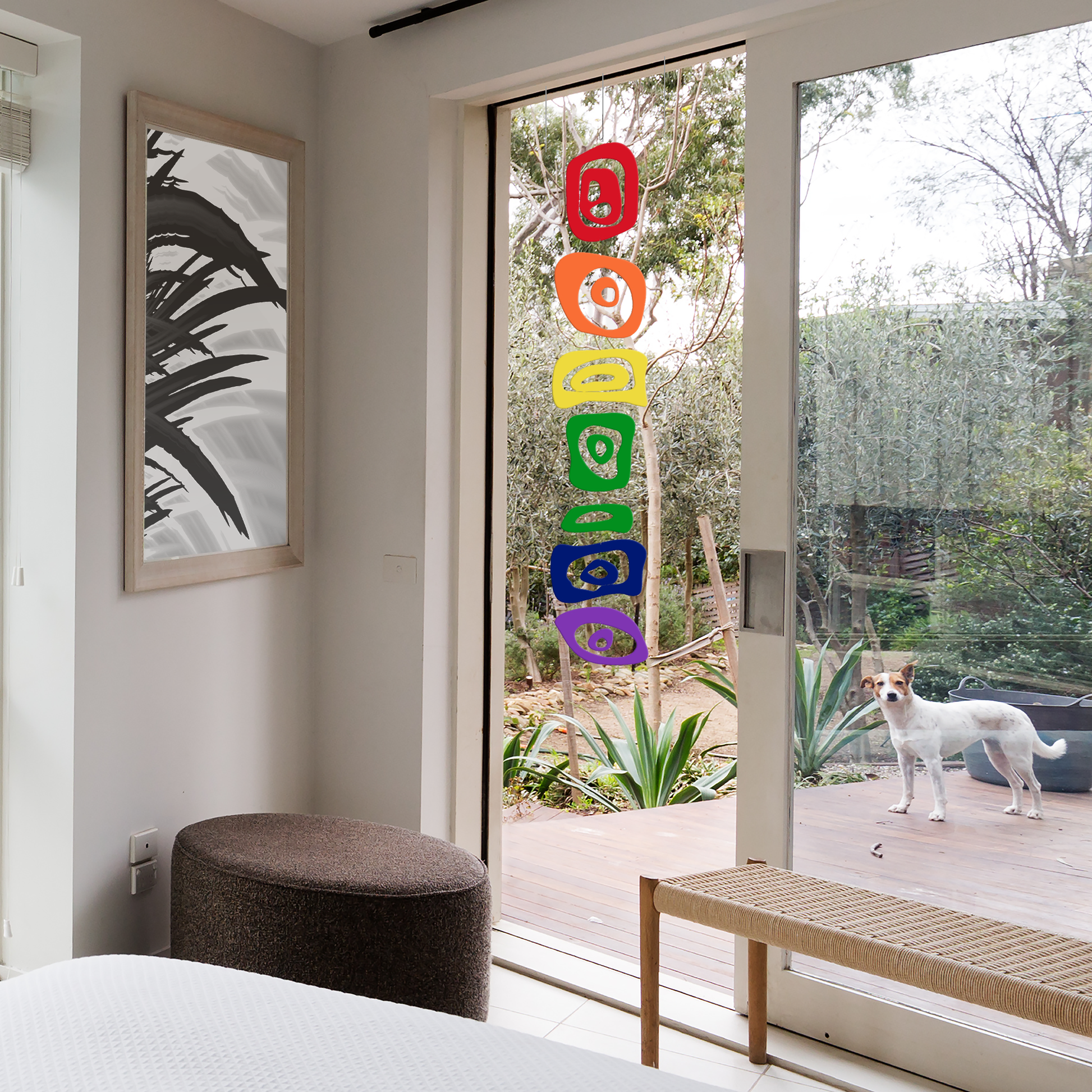 LGBTQ Hanging Art Mobile in bedroom patio window with abstract art and cute dog looking in from the outside - hanging vertical art mobile by AtomicMobiles.com
