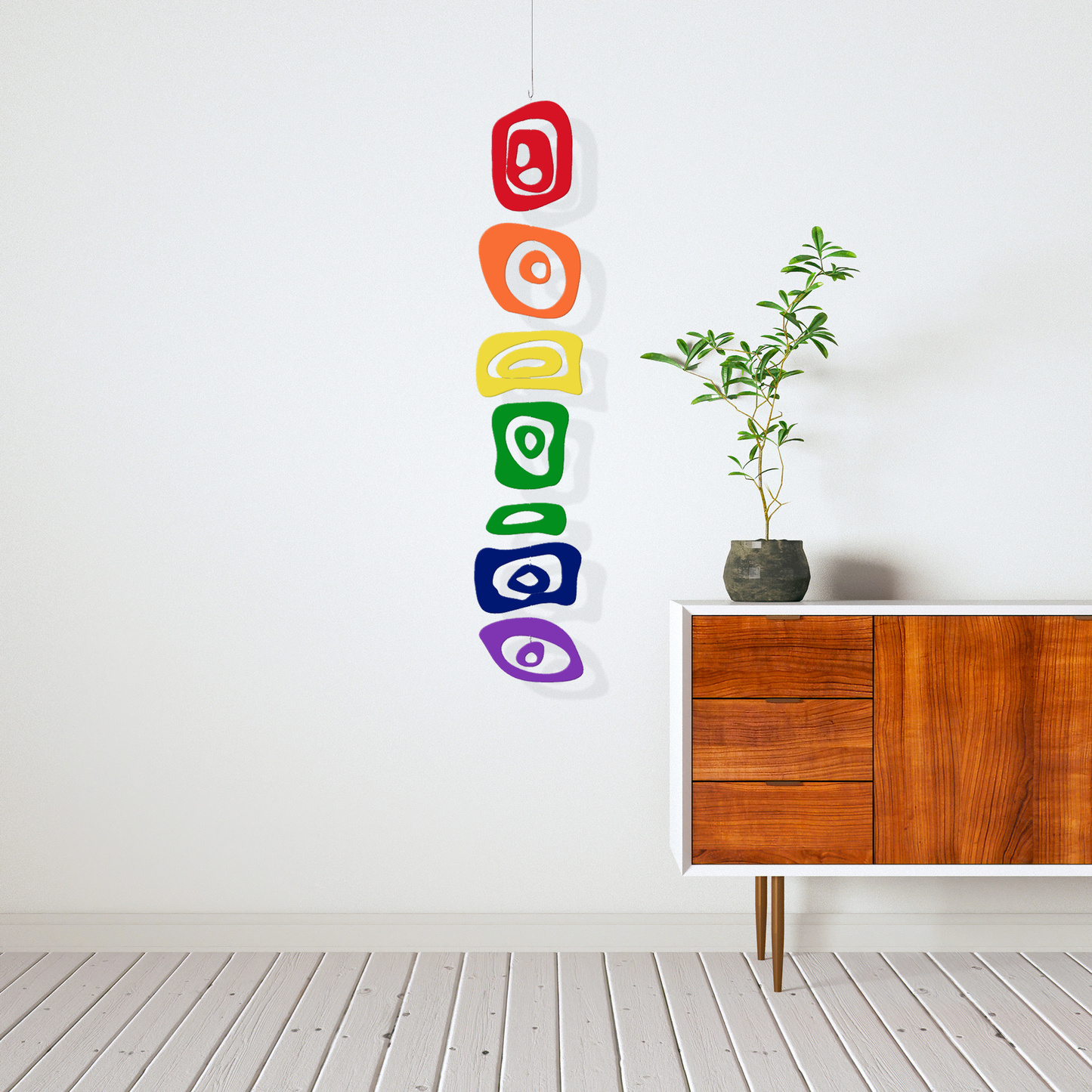 LGBTQ Rainbow Hanging Art Mobile next to mid century modern credenza with zen plant - vertical kinetic art mobile by AtomicMobiles.com