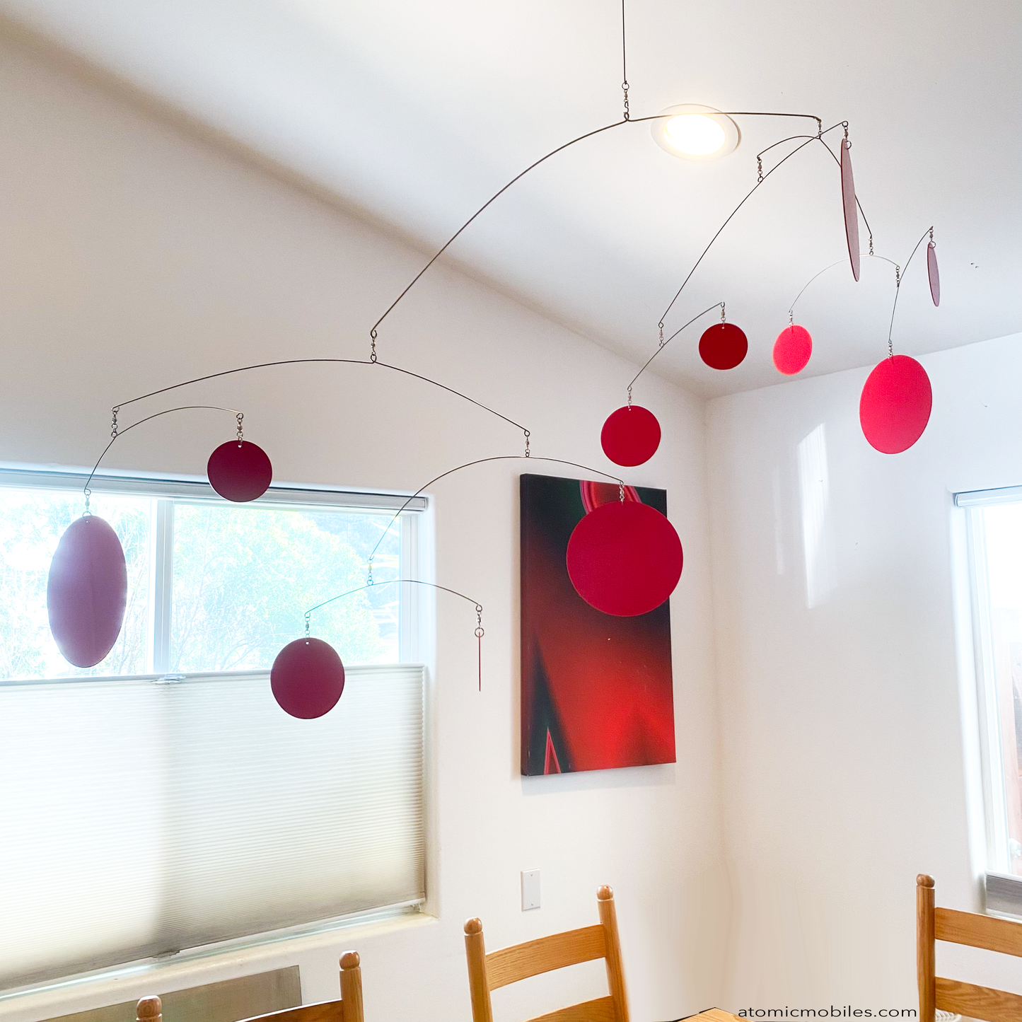 Closeup of XL Red Kinetic Hangng Art Mobile by AtomicMobiles.com - large red circles in large mobile in dining room over wood table made in Los Angeles