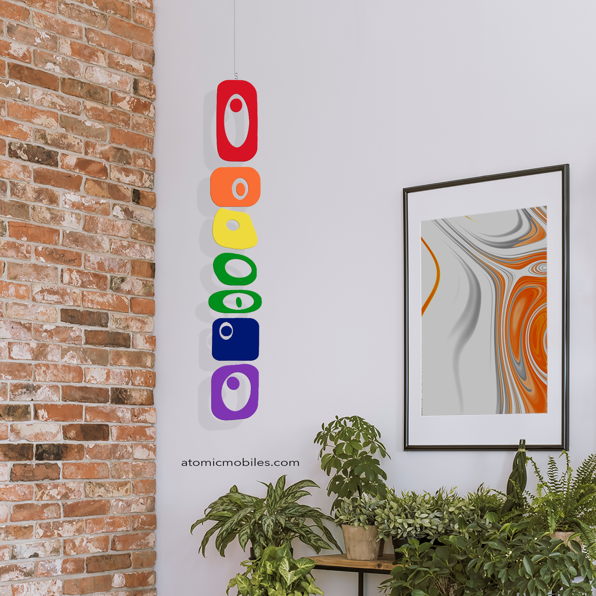 BEATNIK PARTY Rainbow Pride LGBTQ+ Vertical Hanging Art Mobile in room with brick wall, plants and framed abstract art - mobile by AtomicMobiles.com