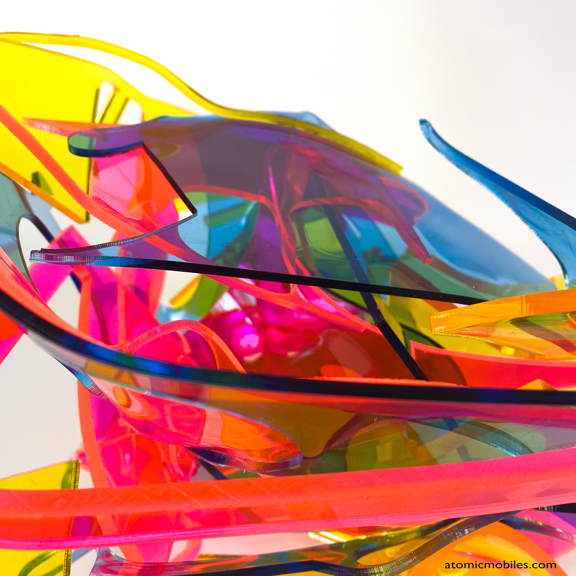 Closeup of bold colorful tabletop abstract modern art sculpture stabile in blue, yellow, hot neon pink, orange, and green featuring entangled acrylic plastic by Debra Ann of AtomicMobiles.com