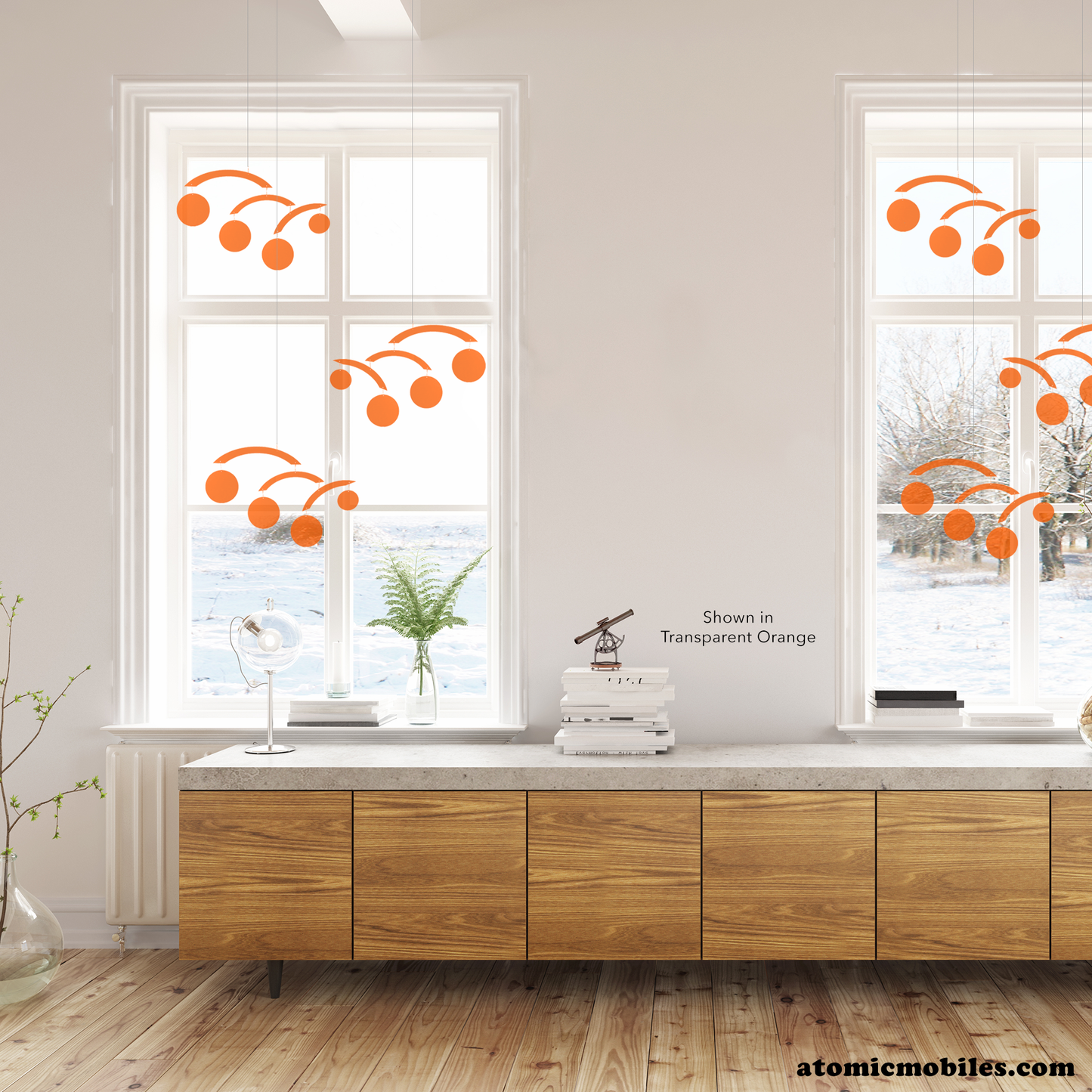 Beautiful modern room with long wood credenza cabinet and two windows featuring 6 transparent acrylic modern kinetic hanging art mobiles -- The Modernist by AtomicMobiles.com