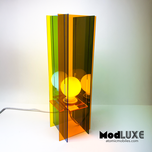 ModLUXE Space Age Lamp in groovy 1970s style and plexiglass acrylic colors of transparent orange, blue, green, and yellow. Colorful lamp with a transparent design on a white background, featuring the brand 'ModLUXE' by AtomicMobiles.com.