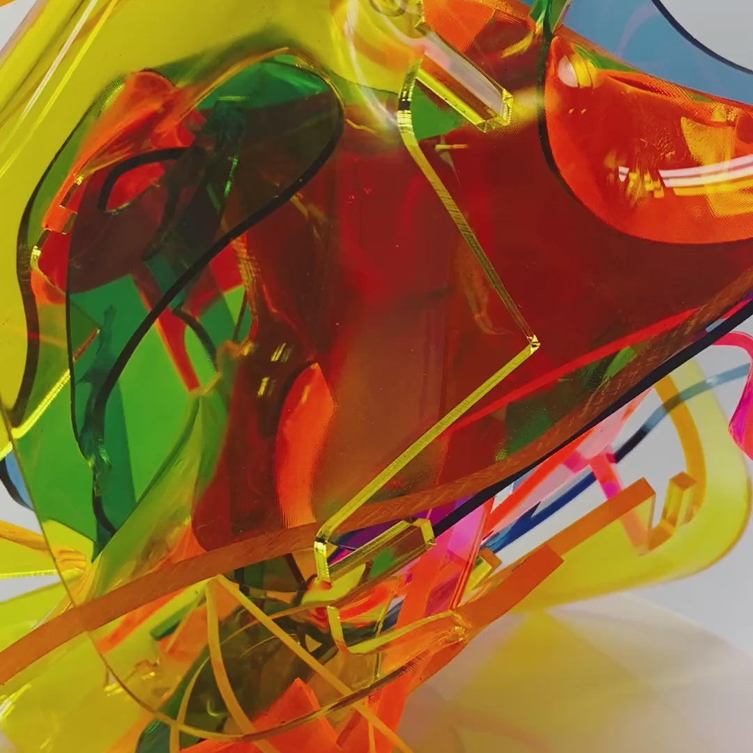 Video of Ecstatic modern art sculpture in bold vibrant colors of yellow, blue, neon pink, orange, and green. Abstract acrylic plastic tabletop art piece by AtomicMobiles.com
