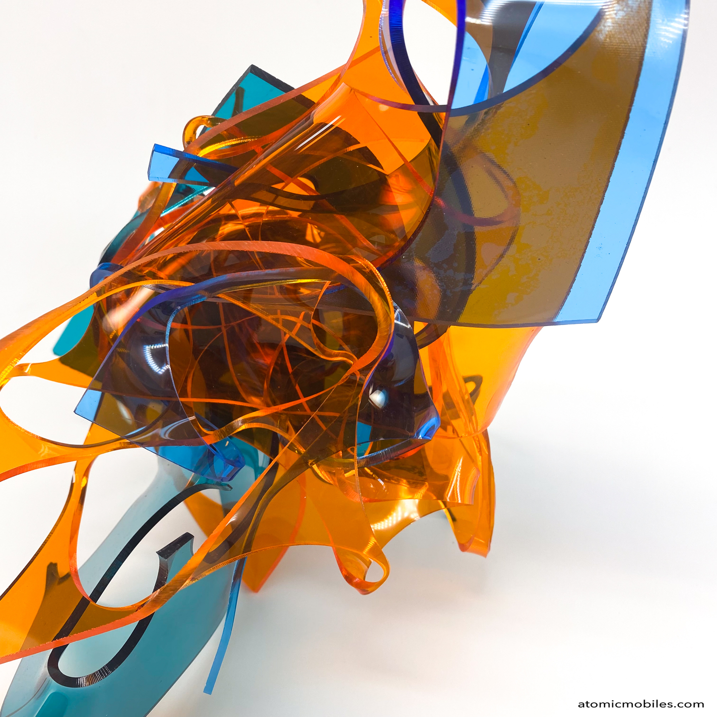 Closeup of Colorful abstract sculpture in transparent orange, teal, and blue plexiglass acrylic on a white background titled Radiance of Water - one of a kind art by Debra Ann of Atomic Mobiles