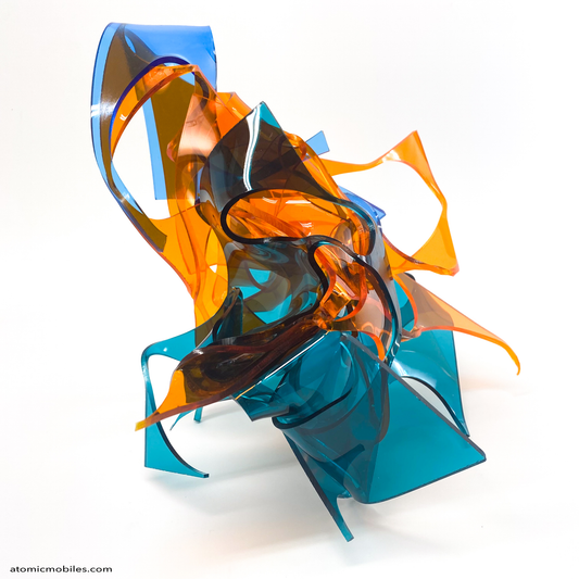 Colorful abstract sculpture in transparent orange, teal, and blue plexiglass acrylic on a white background titled Radiance of Water - one of a kind art by Debra Ann of Atomic Mobiles
