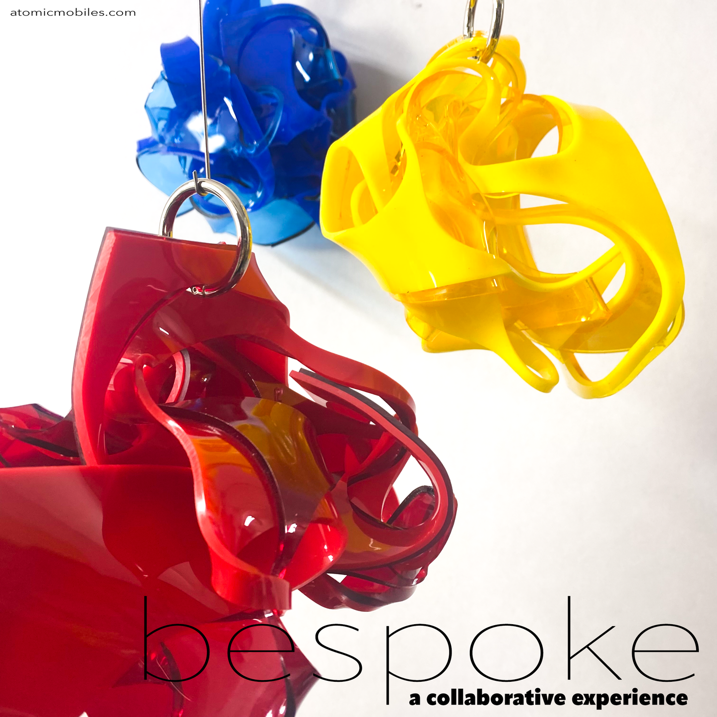 Three colorful plastic mobiles in red, yellow, and blue on a white background with 'bespoke' branding. Bespoke is a collaborative experience, multi color art sculpture shown in blue, yellow, orange, red, and green . You choose your colors for this modern plexiglass art by AtomicMobiles.com