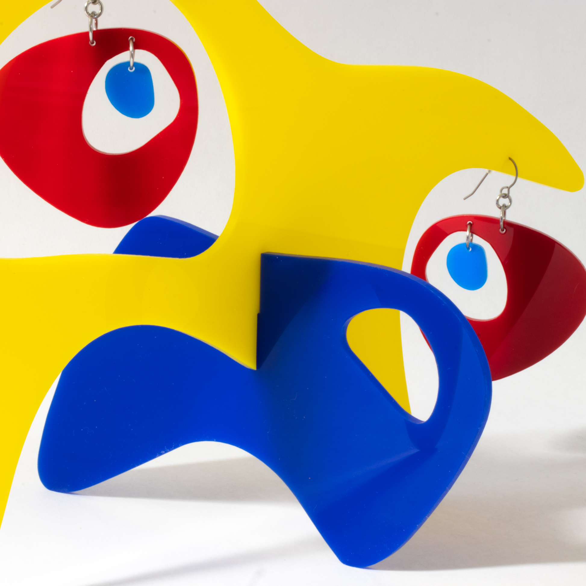 Closeup of yellow, red, and navy blue Googie Earrings in modern art sculpture stabile by AtomicMobiles.com