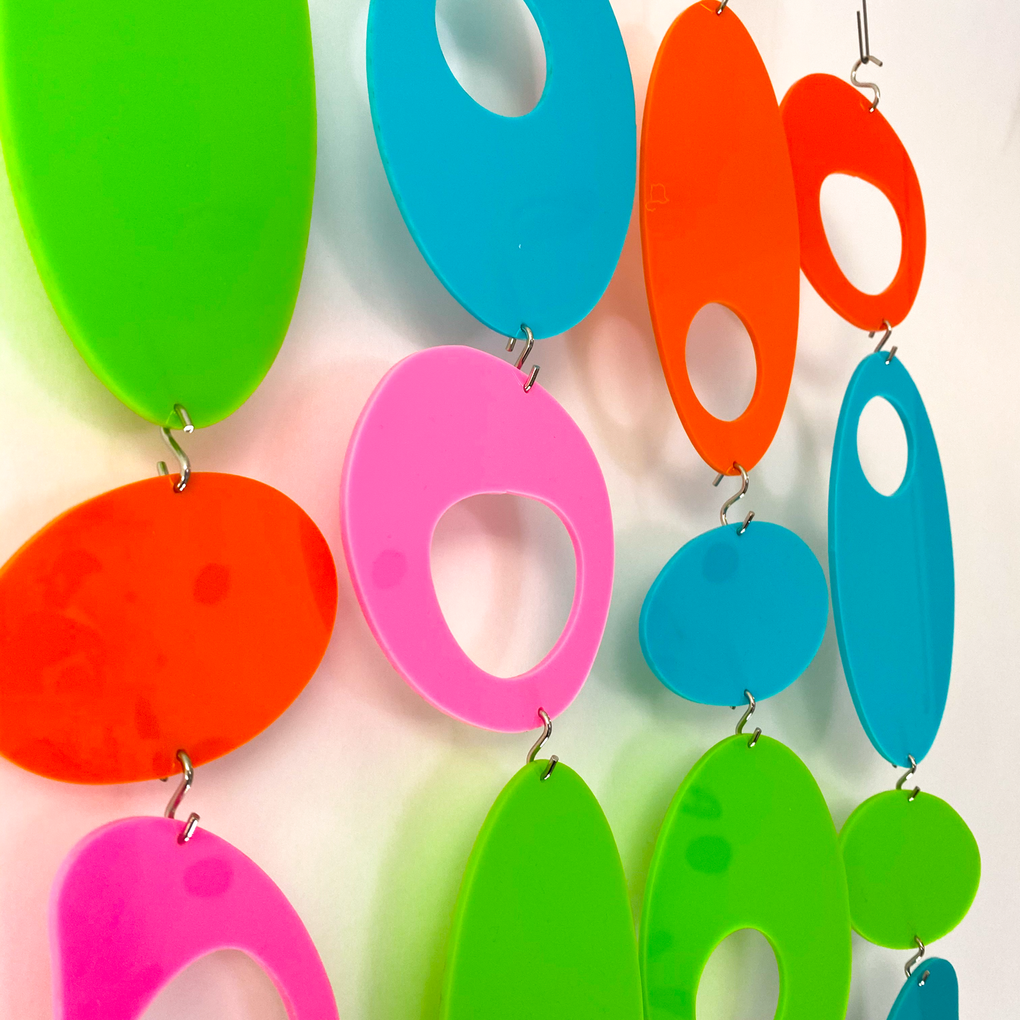 Closeup of Delightful acrylic retro 1970s shapes DIY Kit to create room divider, wall art, curtain, or mobiles in lime, aqua, orange, and hot pink by AtomicMobiles.com