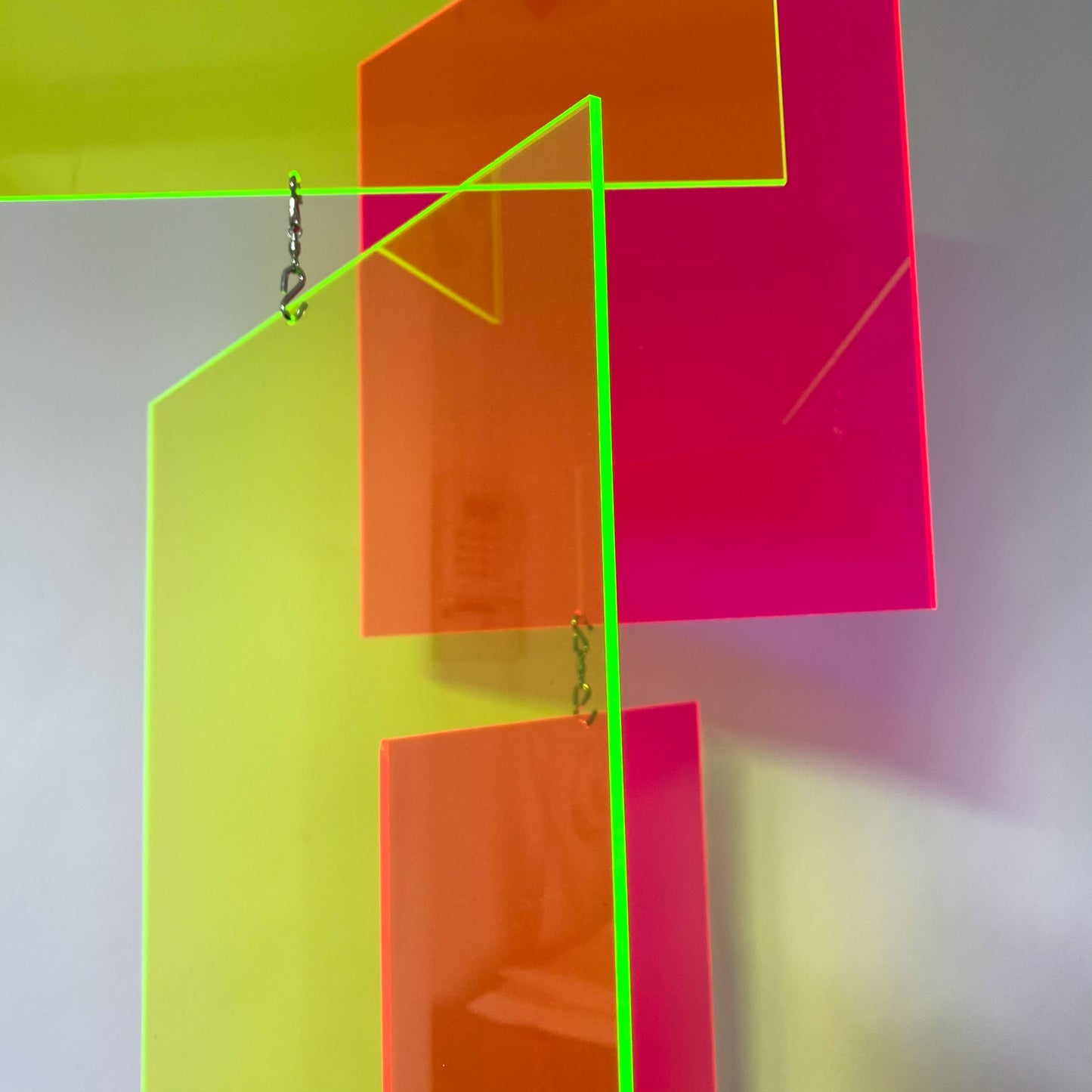 Closeup view of neon fluorescent pink and green kinetic hanging art mobiles by AtomicMobiles.com with edges glowing
